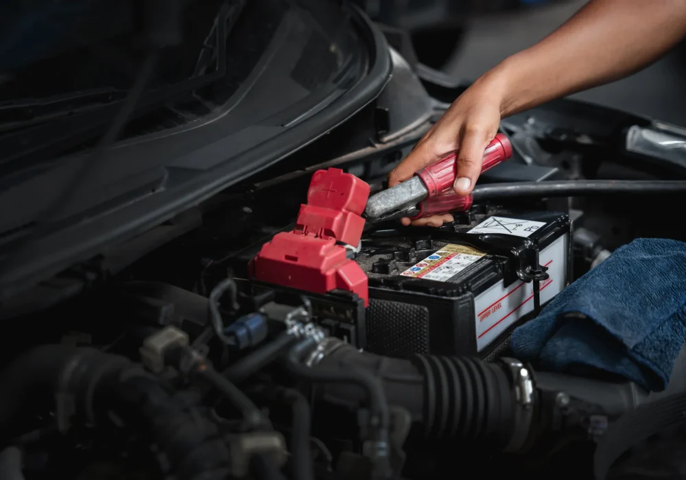 Car Machanic is maintenance on the car in the garage. checking and changing the battery